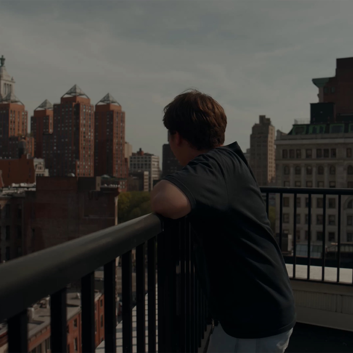 Ian Neyens looking out over the New York City skyline from a balcony